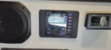 RV rental interior featuring an audio system playing FM 87.5, a speaker, and a Renogy battery monitor at 12.5V.