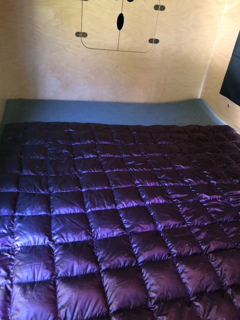Inside a cozy RV rental: a plush purple quilted blanket on a bed, set against light wood walls with a minimalist design. — photo 6