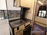 This compact RV rental's interior boasts a functional kitchenette with sink & cooktop, mini-fridge, and a comfy bed.