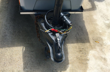 Essential components for an RV rental: close-up of a trailer hitch, featuring the coupler, safety chains, and electrical connector.