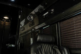 Luxurious RV rental interior with sleek black finishes, comfortable seating, overhead speakers, and privacy blinds.