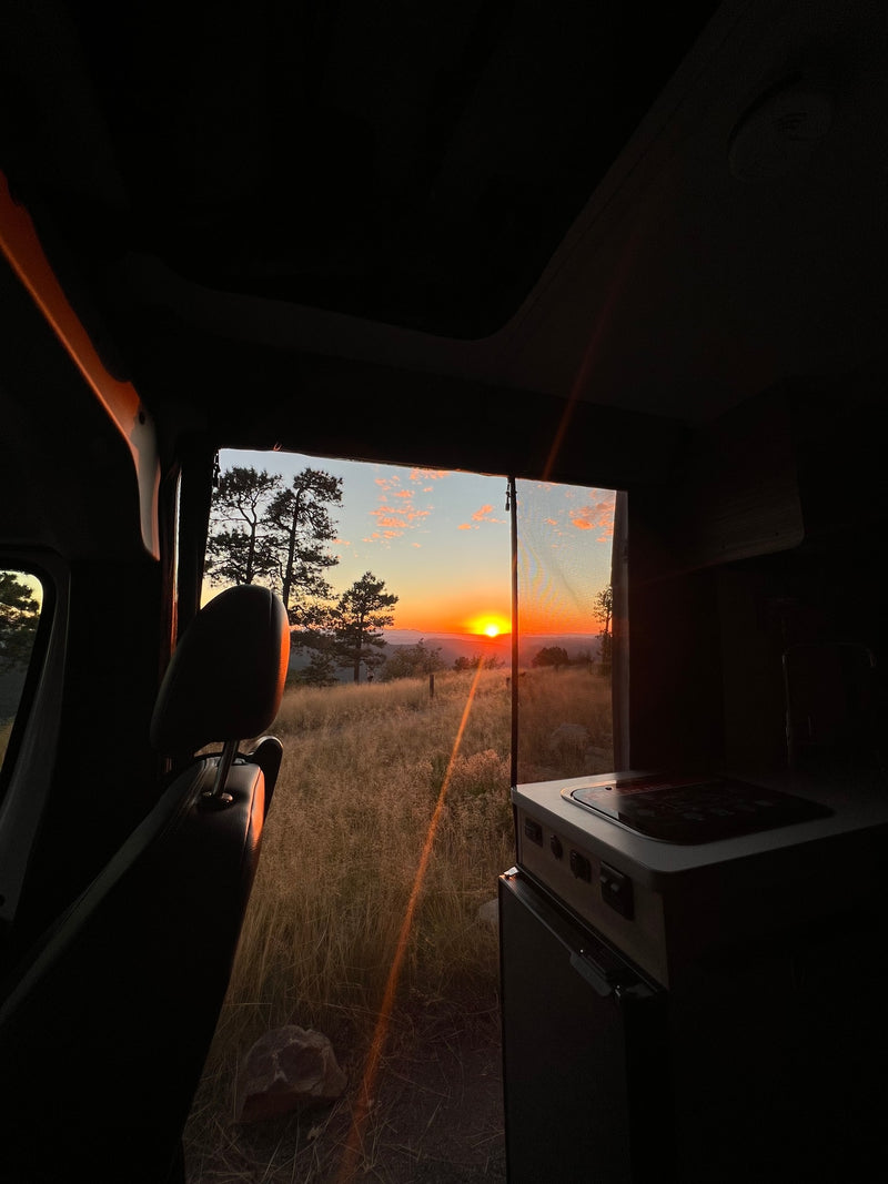  ready for your next RV rental. Parked by desert mountains under a blue sky.|White camper van RV rental gleaming in golden hour sun amidst tall grasses and trees. Your nature adventure awaits!|Stunning sunset from our RV rental. Golden light illuminates a vast — photo 4