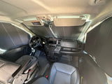 The interior of a modern RV rental van cockpit, featuring a dashboard, steering wheel, seats, and full window sunshades.