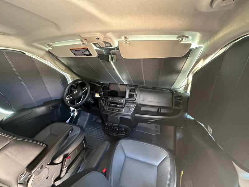 The interior of a modern RV rental van cockpit, featuring a dashboard, steering wheel, seats, and full window sunshades. — photo 6