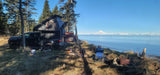 Truck with rooftop camper, an ideal RV rental, enjoys serene waterfront views of snow-capped mountains. A peaceful camping spot.