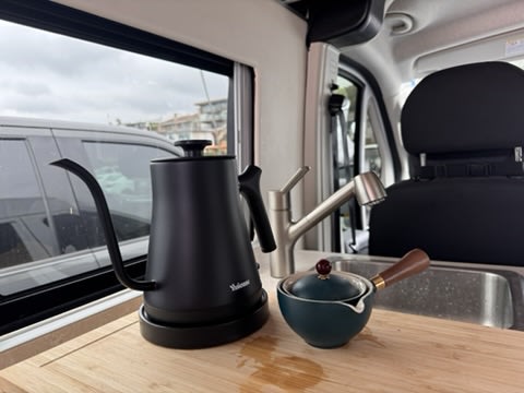 RV rental kitchen featuring a sleek black gooseneck kettle and a small teapot on a wooden counter, ready for coffee or tea.