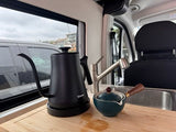 RV rental kitchen featuring a sleek black gooseneck kettle and a small teapot on a wooden counter, ready for coffee or tea.
