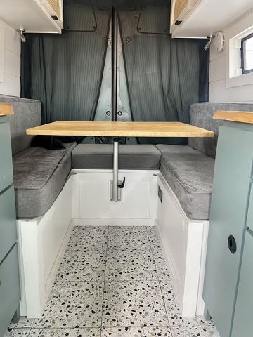 Step inside this RV rental! Features a modern dining area with a wooden table & grey cushioned seating.