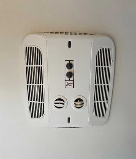 Stay cool in your RV rental! Ceiling-mounted Coleman Mach climate control unit with fan/temp knobs, vents & light switch.