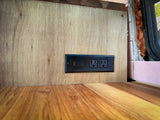 RV rental: Modern wooden wall with a built-in power strip featuring USB-A, USB-C, and two AC outlets for charging devices.