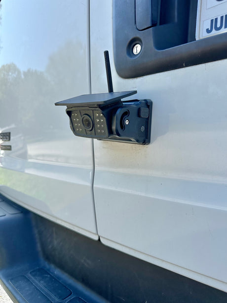 Close-up of a solar-powered security camera with an antenna on a white RV rental door, enhancing vehicle safety.