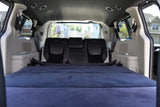 Cozy vehicle interior, perfect for an RV rental. Blue mattress laid over folded seats creates a comfy sleeping area.
