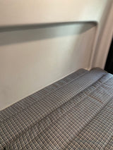 Inside an RV rental, a sleeping area with patterned gray cushions against a light, textured wall.