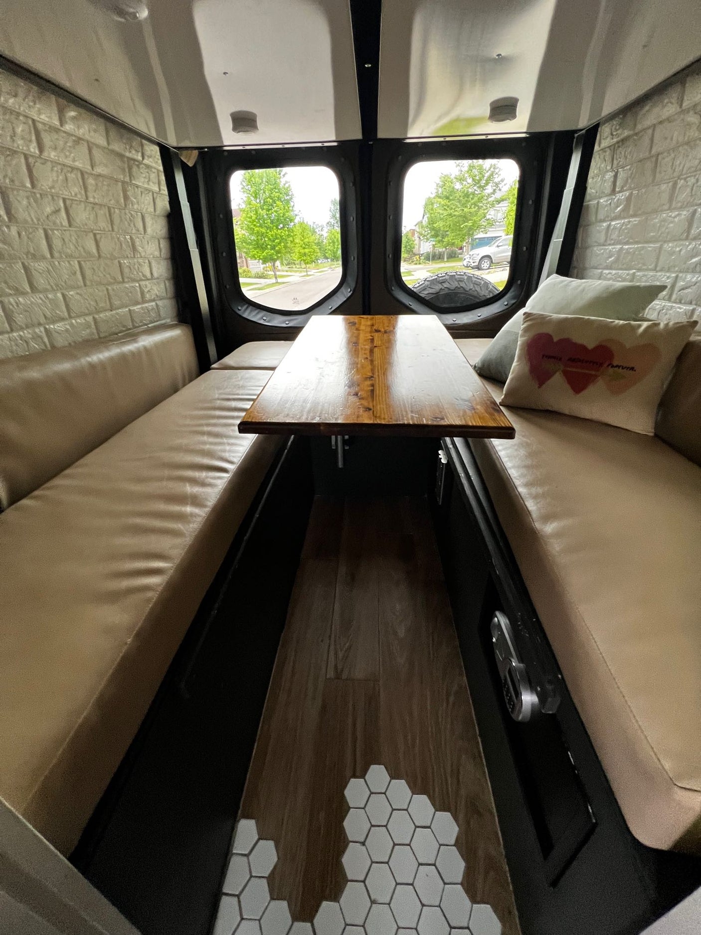 Cozy RV rental interior with bench seating, a wooden table, and scenic rear windows.