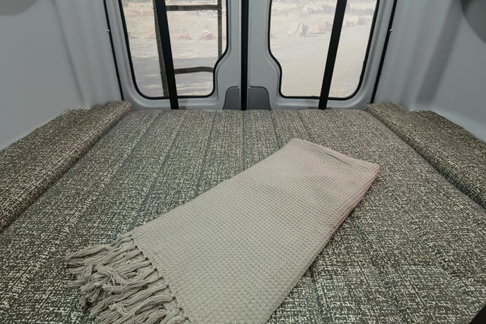  including dedicated bike space.|Inside an **rv rental**: a compact dining area with bench seating and a swiveling driver/passenger seat at a small table.|Snow-covered Sprinter camper van for rv rental — photo 19