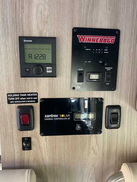 RV rental interior: A detailed RV control panel with Truma, Winnebago, & Xantrex displays for tanks, power, and heating systems.