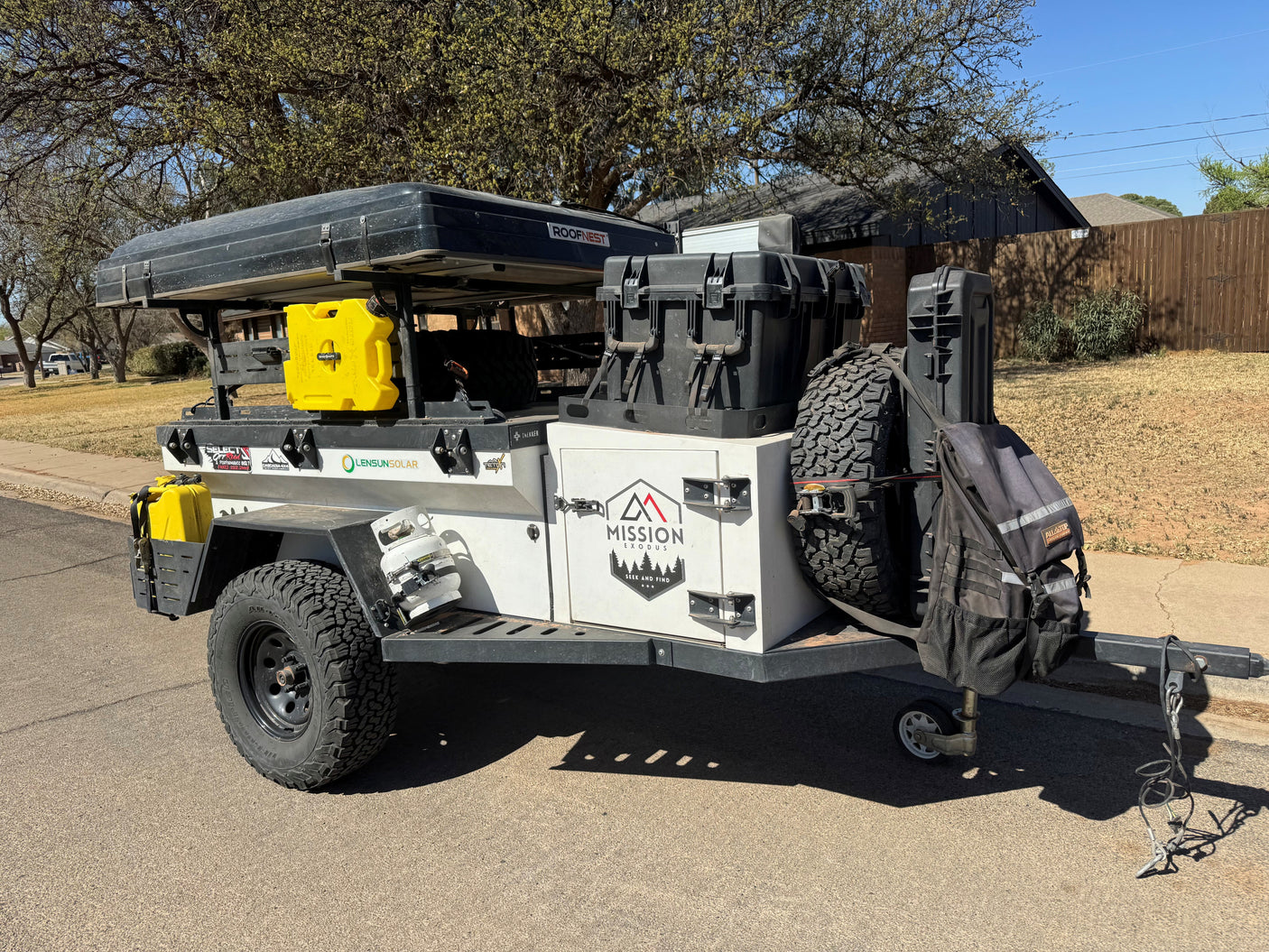 This rugged overland camping trailer, like an RV rental, features a Roofnest tent, spare tire, and ample storage.