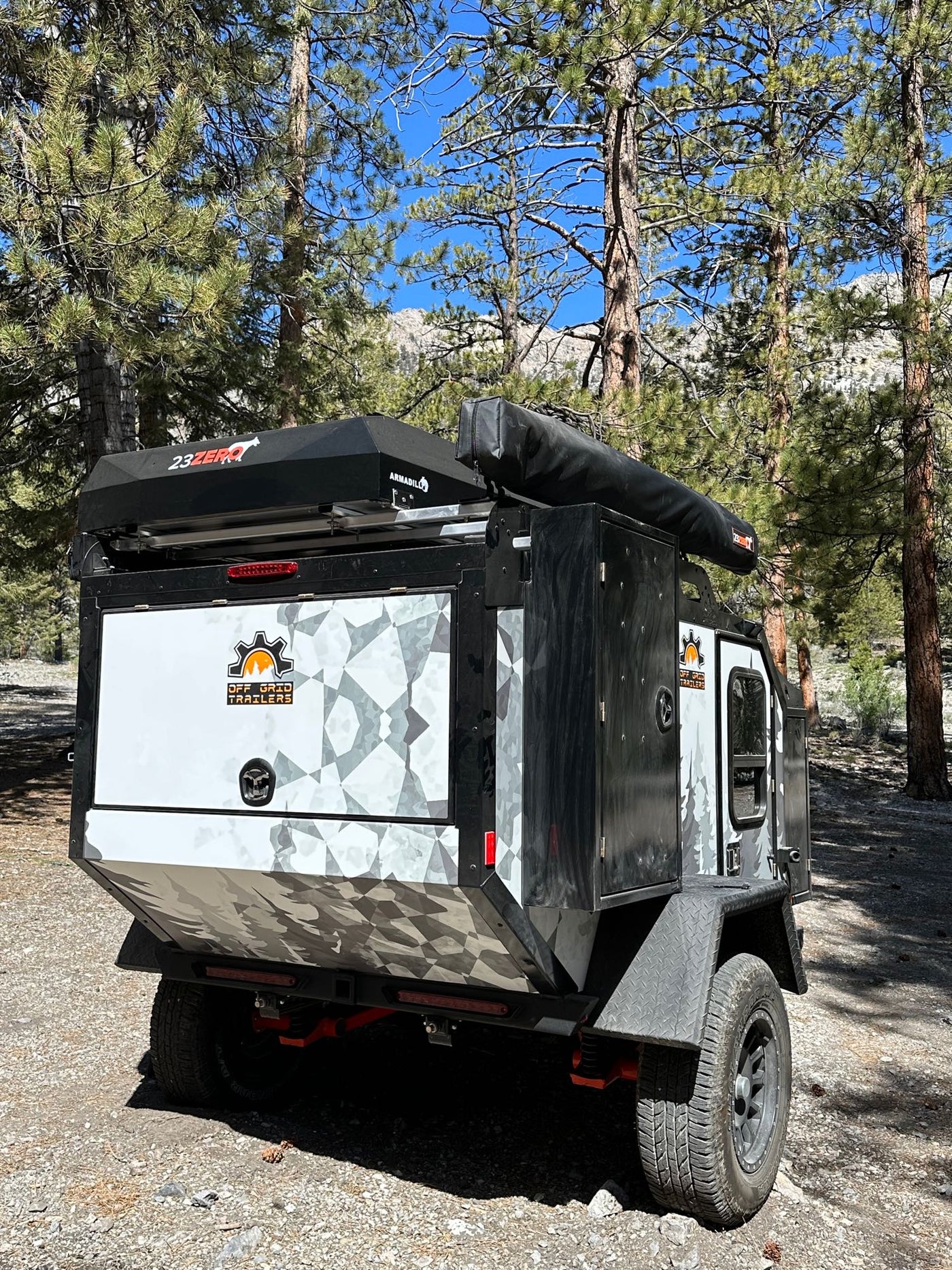Explore off-grid! This rugged overland trailer, available for RV rental, parked amidst pines for mountain camping. — photo 11