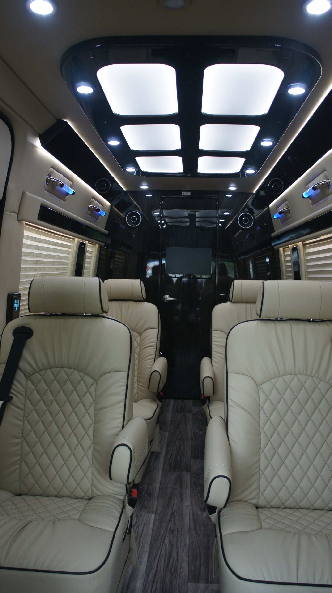 Spacious RV rental interior: Cream quilted leather seats, bright overhead lighting, and entertainment. Experience luxury travel.