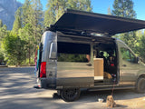 A Storyteller Overland camper van RV rental with two dogs enjoying a natural outdoor adventure setup.