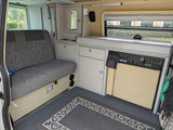 Inside an RV rental: versatile camper van interior with a convertible bench seat, compact kitchen, and integrated storage.