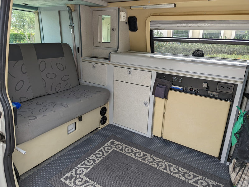 Inside an RV rental: versatile camper van interior with a convertible bench seat, compact kitchen, and integrated storage. — photo 19