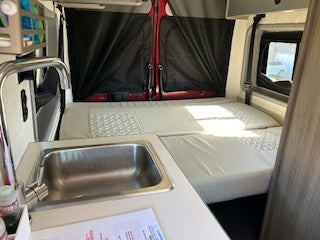  and comfortable seating leading to the living area.|Inside a cozy RV rental kitchen with sink