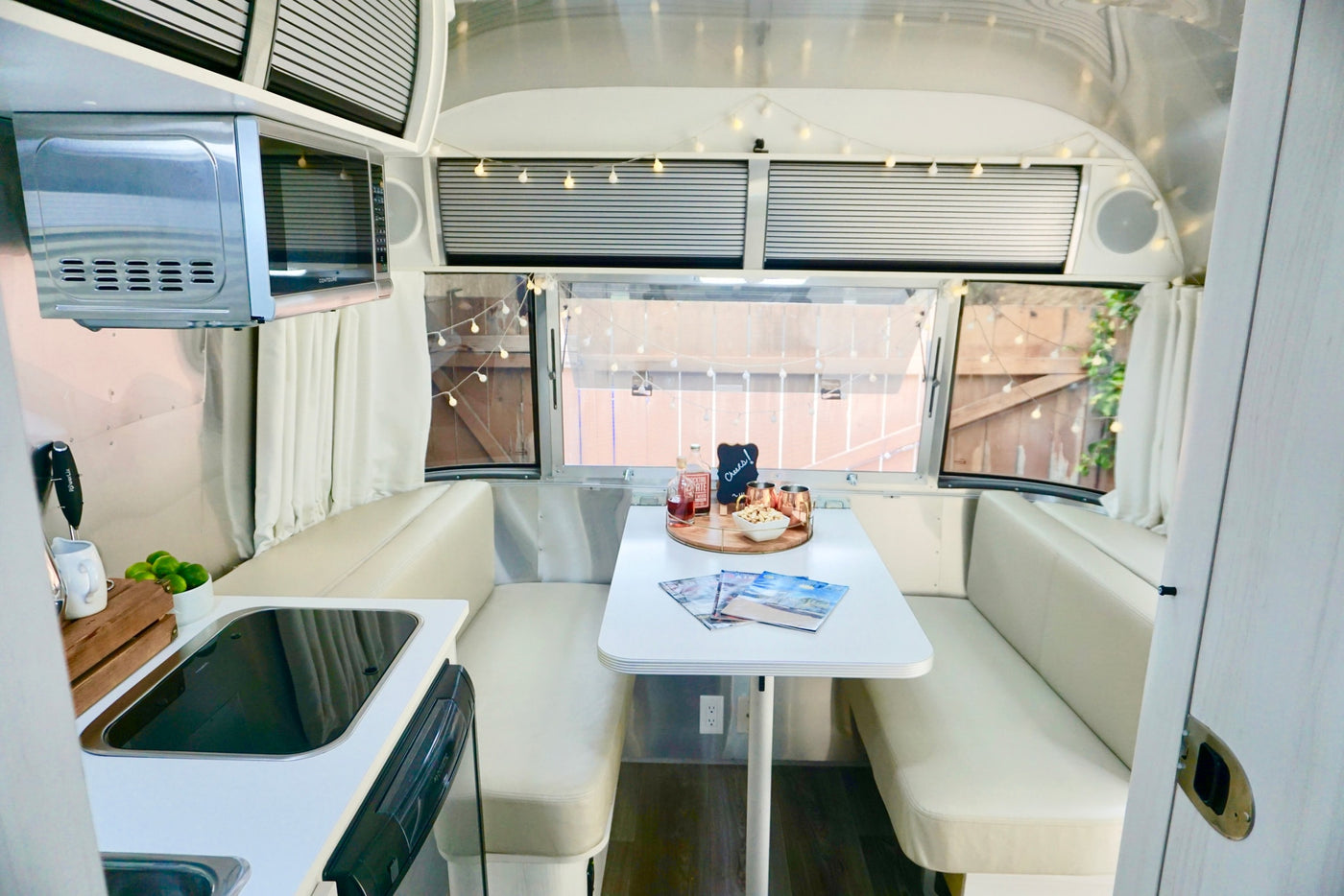 Cozy Airstream RV rental interior, featuring a bright kitchen & comfortable dinette with charming string lights. — photo 12