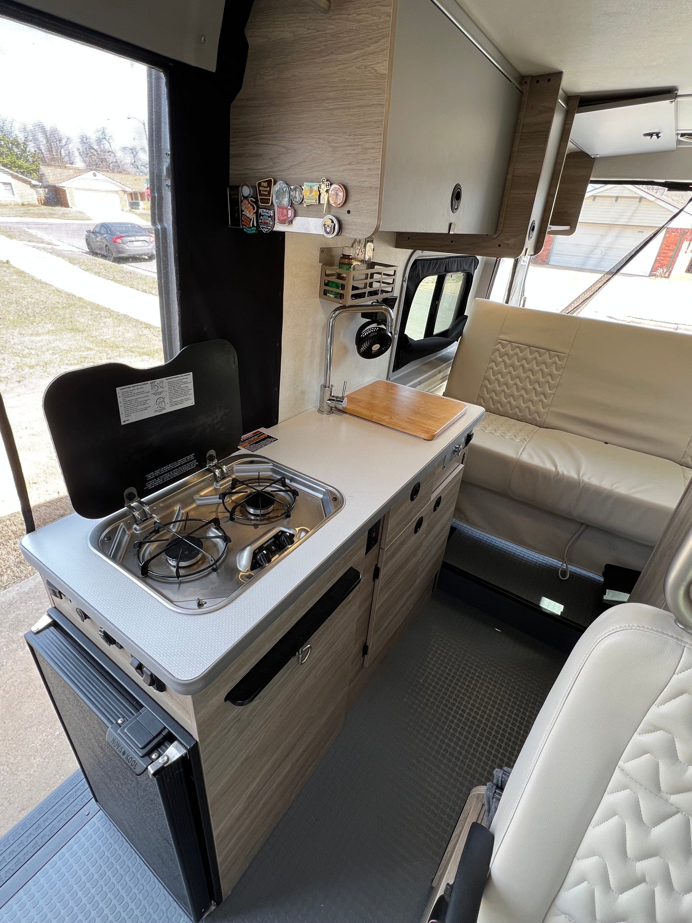 Modern RV rental interior: compact kitchen with stove, sink, and fridge, plus comfy seating for travel. — photo 3