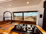 Modern RV rental kitchen with a sleek faucet, built-in stove, and a scenic desert mountain window view.