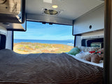 Enjoy an ocean view from your cozy RV rental bed, complete with soft blankets and fun plush toys. Ideal for a coastal retreat.
