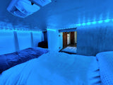 Cozy RV rental sleeping nook with blue LED strip lights illuminating the bed and interior.