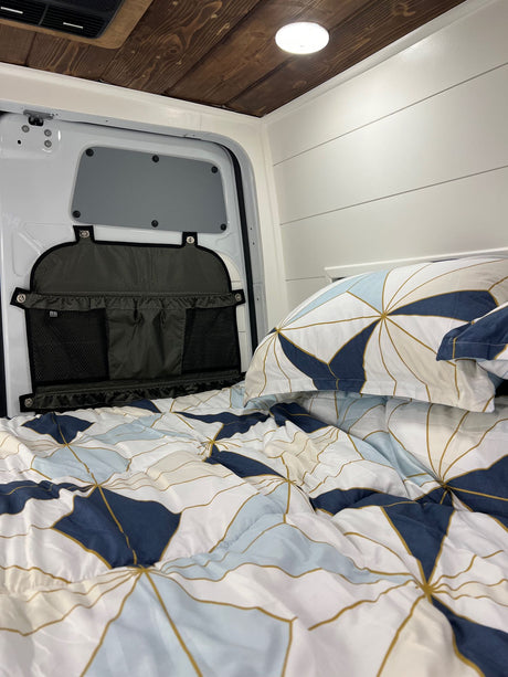 Inside a cozy RV rental: comfy bed with unique linens, plus smart storage on the back door for organized travel.