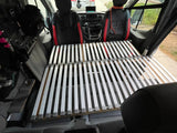 Inside an RV rental van featuring front seats and a convertible slat bed base, ideal for camping and road trips.
