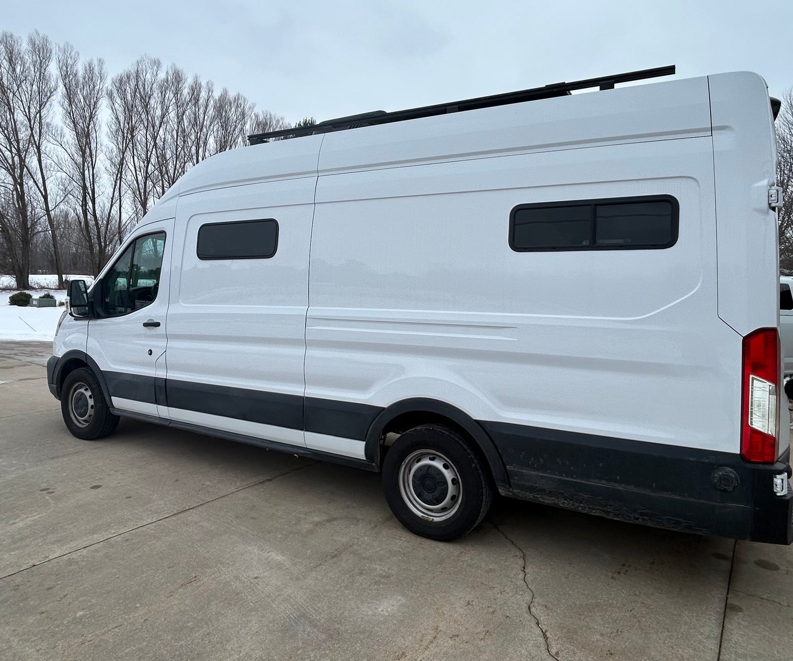 White camper van with a roof rack and custom windows, perfect for an RV rental adventure.