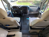 Spacious RV rental cabin with light leather seats, modern dashboard, and clear views, ready for your next adventure.