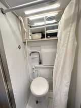 Inside an RV rental: a compact wet bath with a toilet, shower, and small sink, designed for efficient use of space.