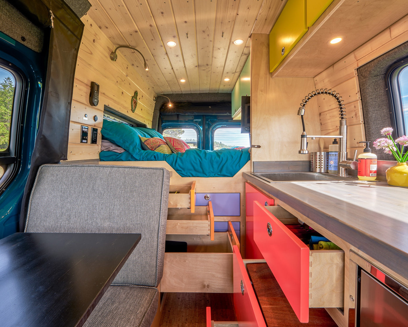 Colorful RV rental interior featuring a kitchen, bed area, and modular storage for a comfortable camper experience. — photo 10
