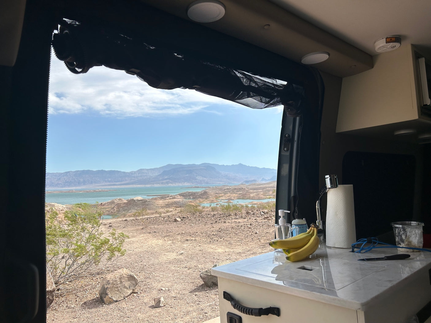 Enjoying a stunning desert lake view from inside an RV rental, complete with kitchen and scenic mountains.