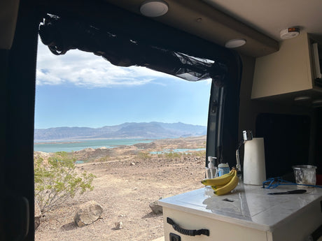 Enjoying a stunning desert lake view from inside an RV rental, complete with kitchen and scenic mountains.