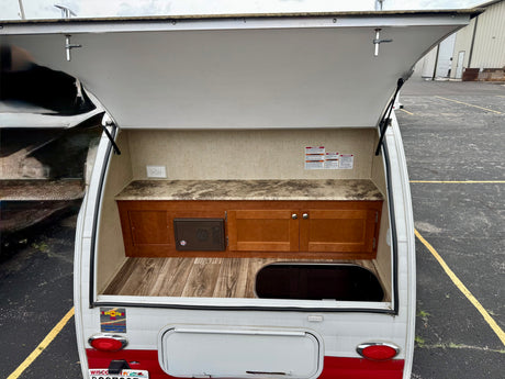 RV rental: Open rear hatch reveals outdoor kitchen with countertop, cabinets, power outlet, and floor basin.