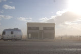 An RV rental, a silver Airstream, parked next to the famous Prada Marfa art installation in the Texas desert.
