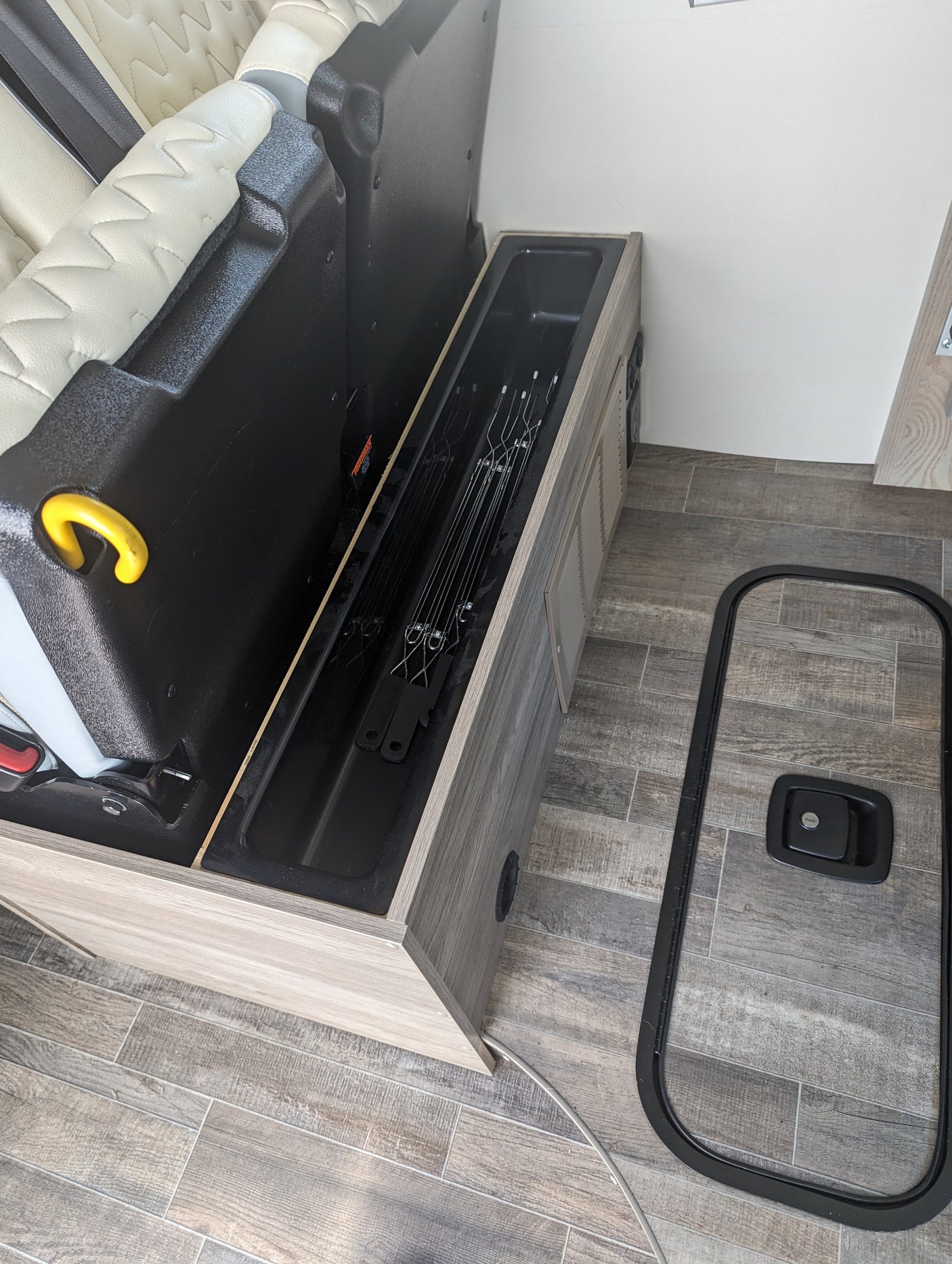 RV rental interior showing clever hidden storage for poles and a removed floor hatch cover, maximizing space.