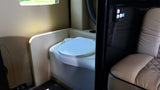 This RV rental features a compact interior with a white toilet, tan cushioned seat, and a lighted black control panel.