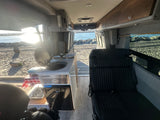 Storyteller Overland RV rental interior with kitchen, seating, & beach view. Perfect for van life adventures by the ocean.
