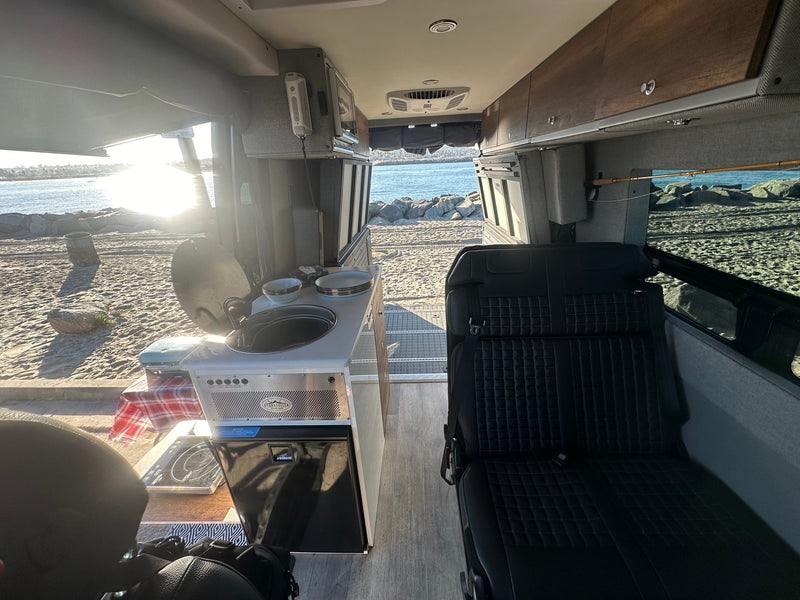 Storyteller Overland RV rental interior with kitchen, seating, & beach view. Perfect for van life adventures by the ocean. — photo 15