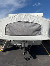 Front view of a white pop-up camper for RV rental, showing its fabric top, mesh window, and hitch.