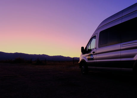RV rental adventure: a WanderVans camper van parked at dusk, showcasing silhouetted mountains and a vibrant sky.