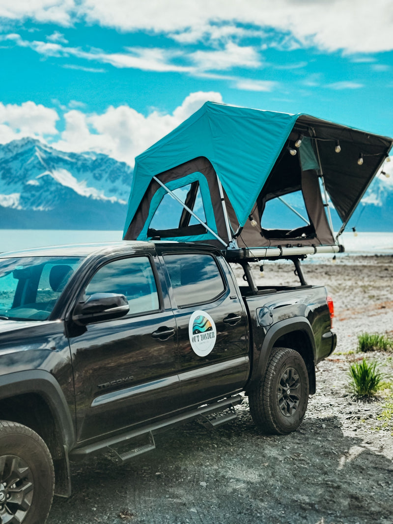 RV rental: Black pickup truck with a vibrant teal rooftop tent set up by a serene lake with majestic mountains beyond. — photo 8