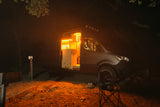 A modern RV rental camper van parked at night, with its side door open, revealing a warm, glowing interior kitchen. Ready for adventures.